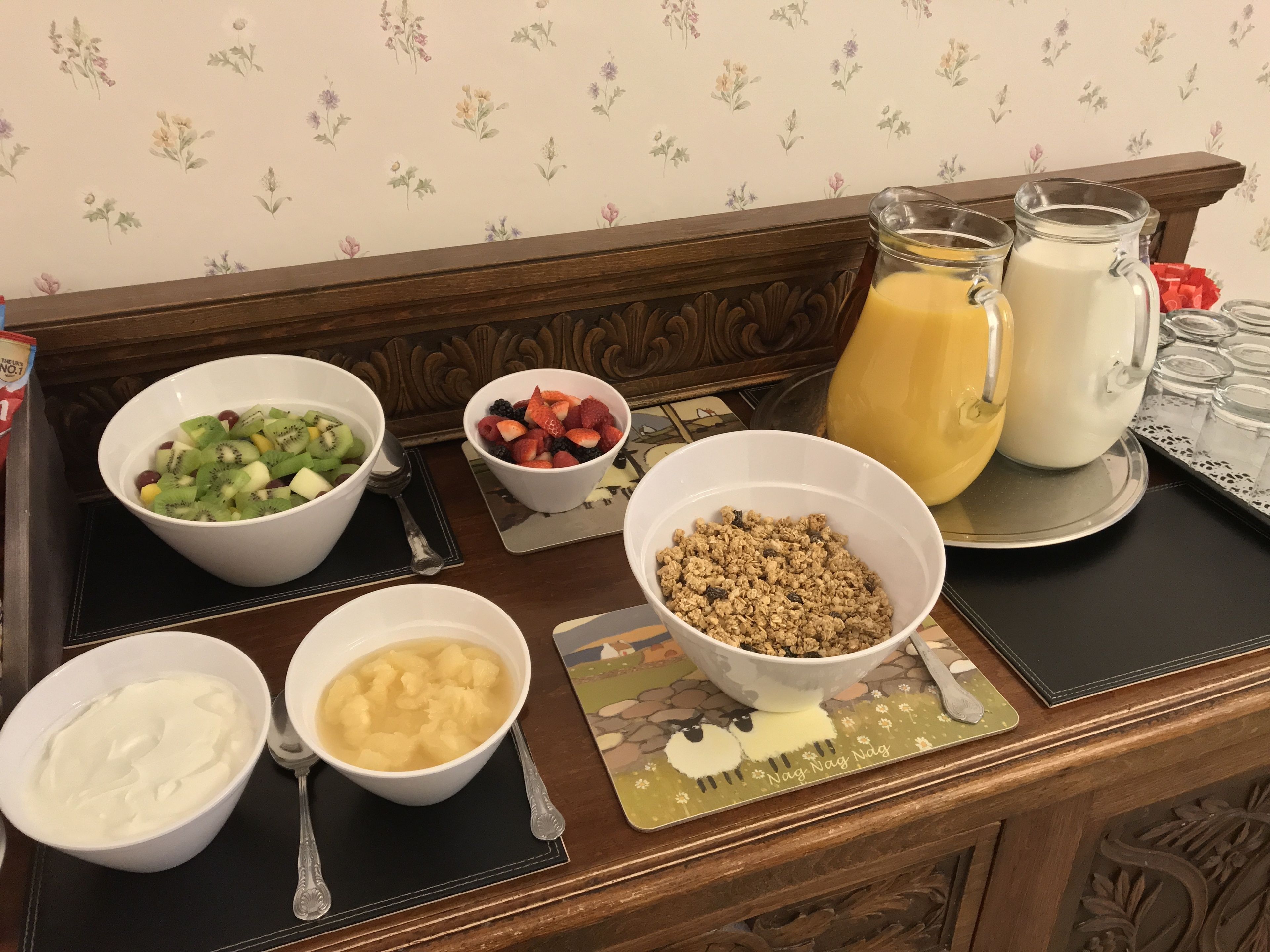 A breakfast table with various food items and drinks.