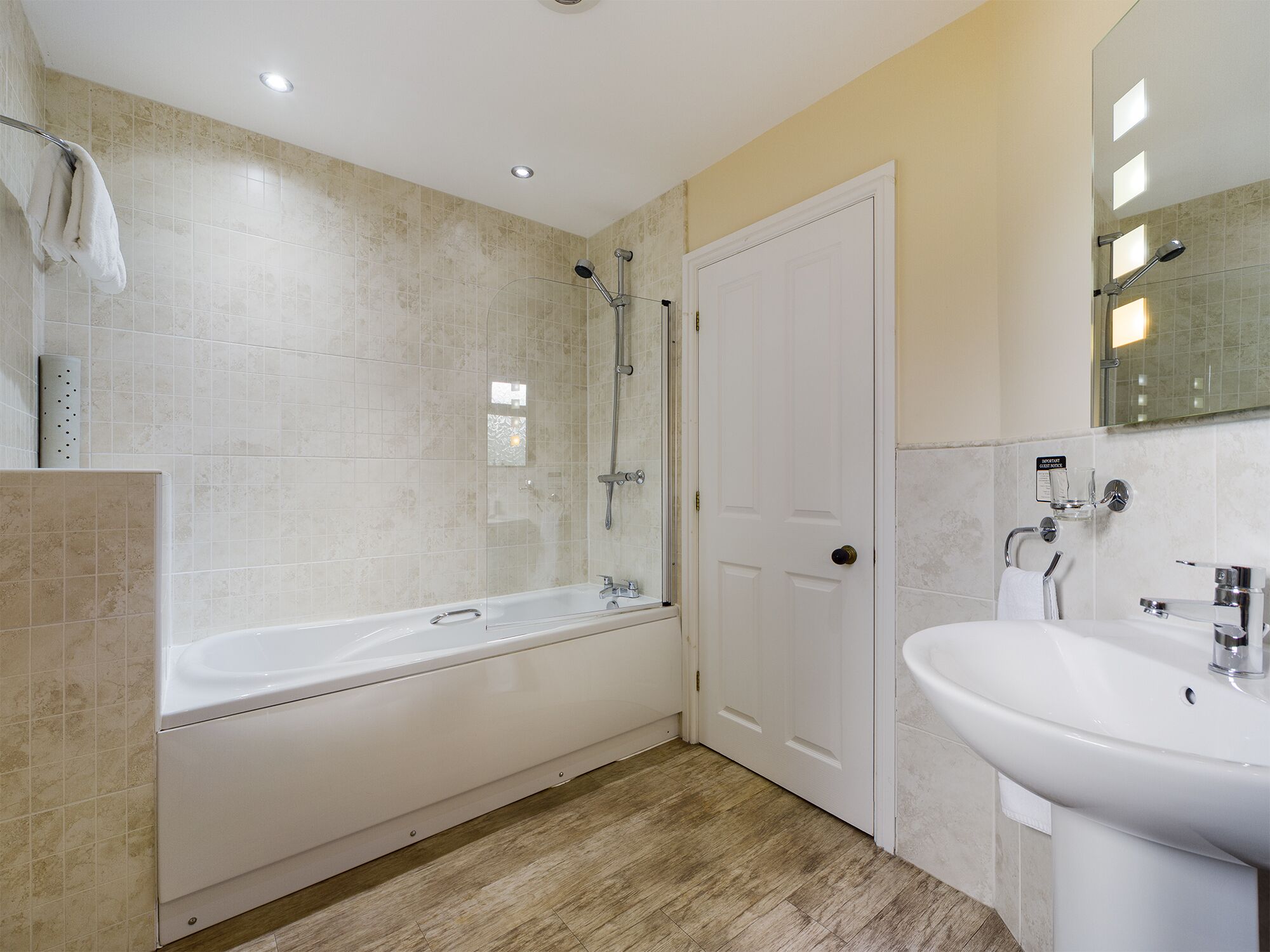Een moderne badkamer met een bad, douche en wastafel.