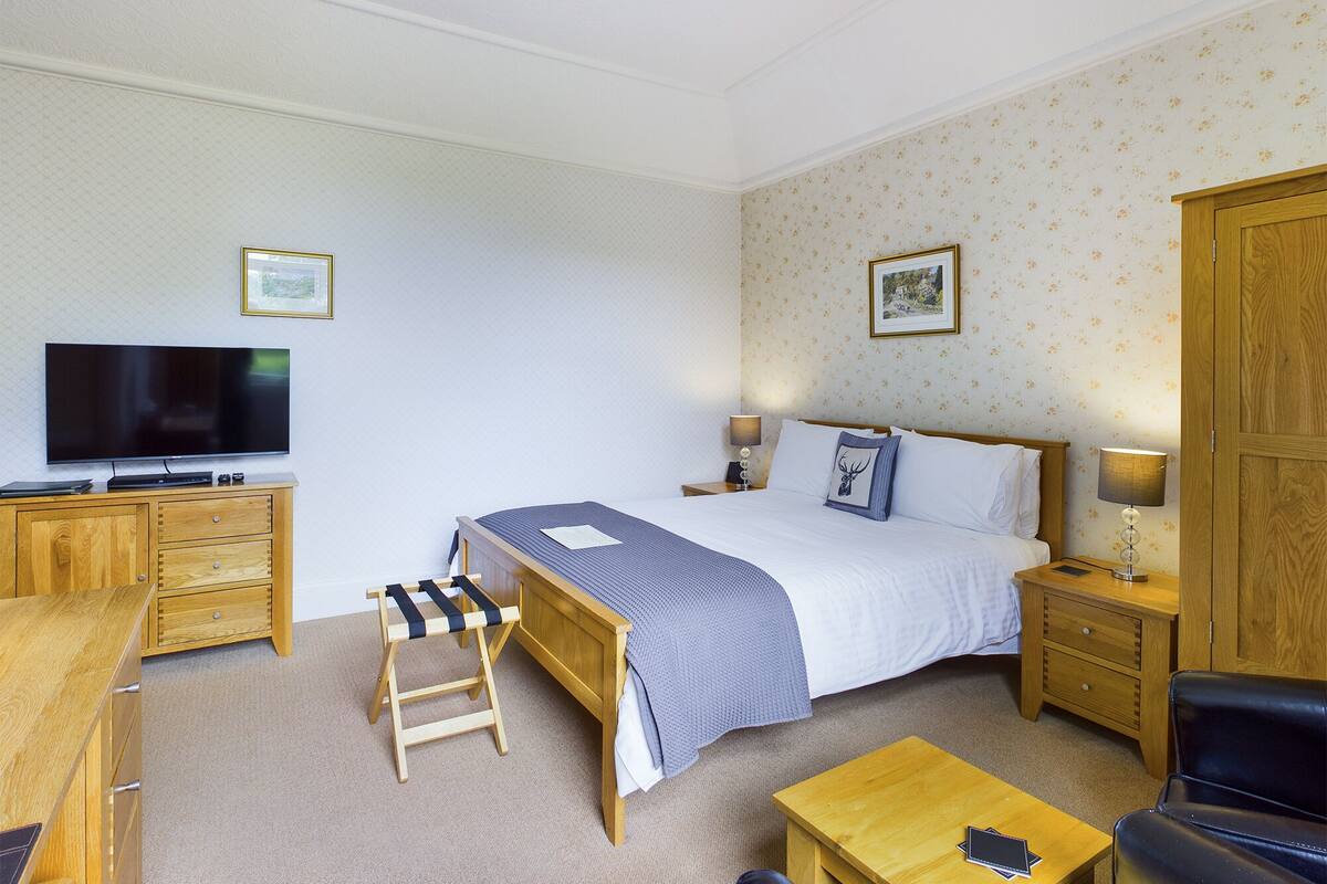 Une chambre d’hôtel équipée d’un lit, de tables de chevet, d’une télévision, d’un bureau, d’une chaise et d’une armoire.