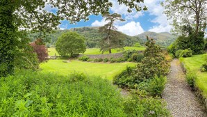 A lush green landscape with a gravel path, trees, and a stone wall. - Crow How Country Guest House (Ambleside)