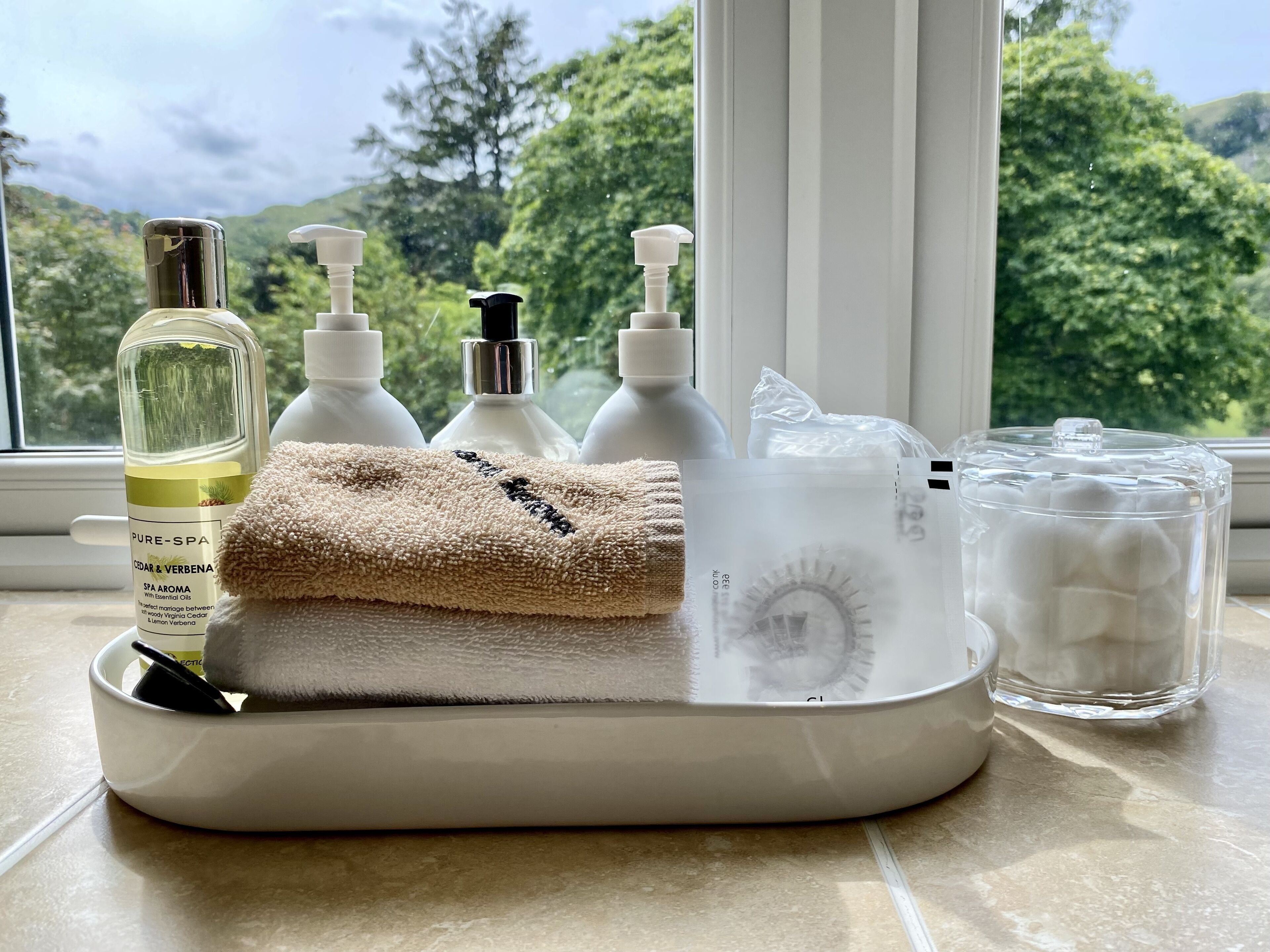 A bathroom vanity with a window view, a towel, and various toiletries.