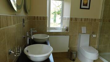 A bathroom with two sinks, a toilet, a window, and a radiator.