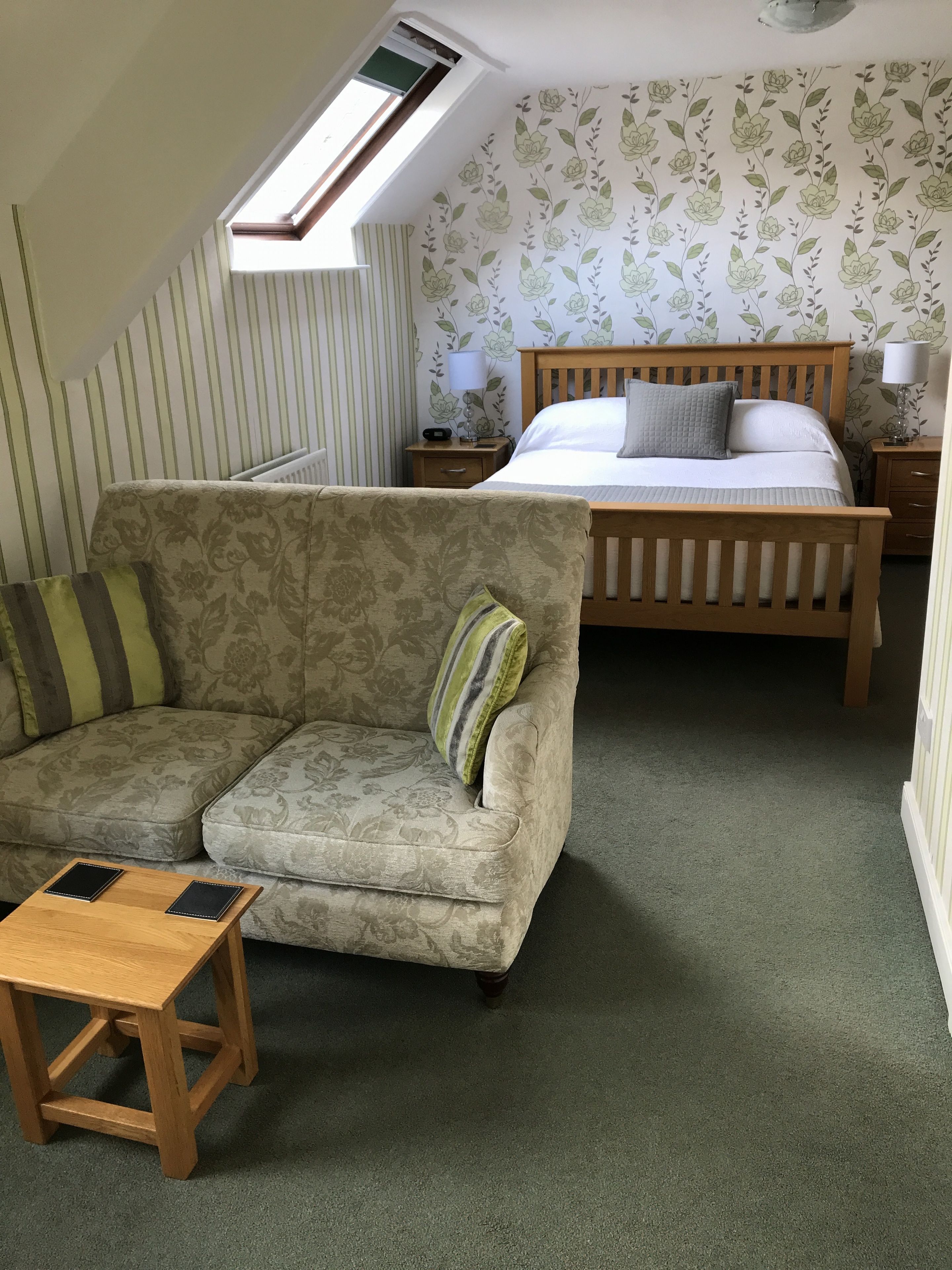 A cozy room with a sofa, a small wooden table, a bed, and a nightstand.
