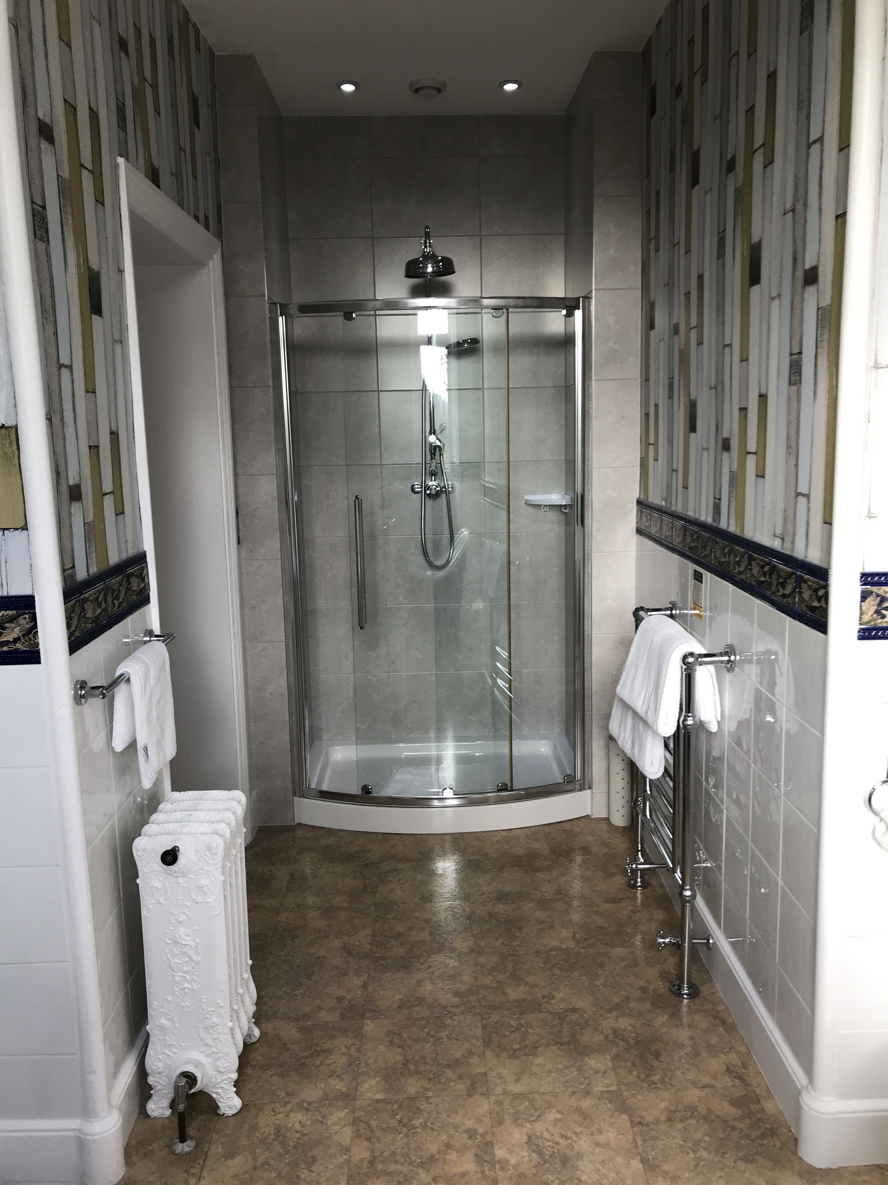 A modern bathroom with a glass-enclosed shower, a white bathtub, and a towel rack.