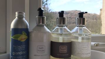 Four bottles of bath products on a windowsill.