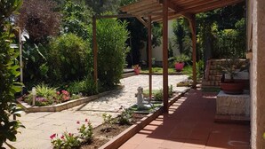 A garden with a pergola, a statue, and various plants.