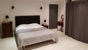 A bedroom with a bed, bedside tables, a dresser, a door, and a curtain.