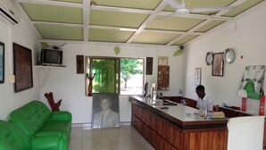 A room with a green sofa, a wooden desk, a ceiling fan, and a framed picture on the wall. - Hotel Vilcabamba (Ho)