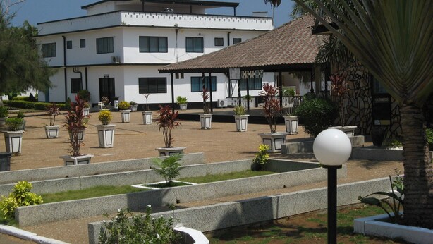 A courtyard with a white building, potted plants, and a gazebo. - Hotel Vilcabamba (Ho)
