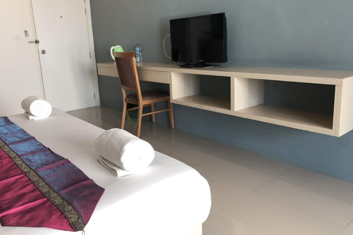 Een hotelkamer met een bed, een bureau, een stoel, een televisie en een waterfles.