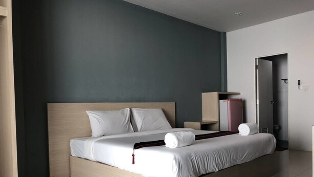 Una habitación de hotel moderna con una cama grande, una mesita de noche y un armario.