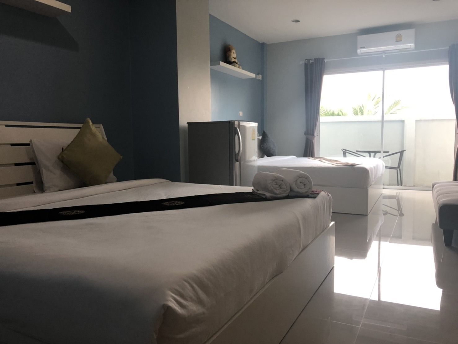 A hotel room with two beds, a refrigerator, a small table, and a chair.