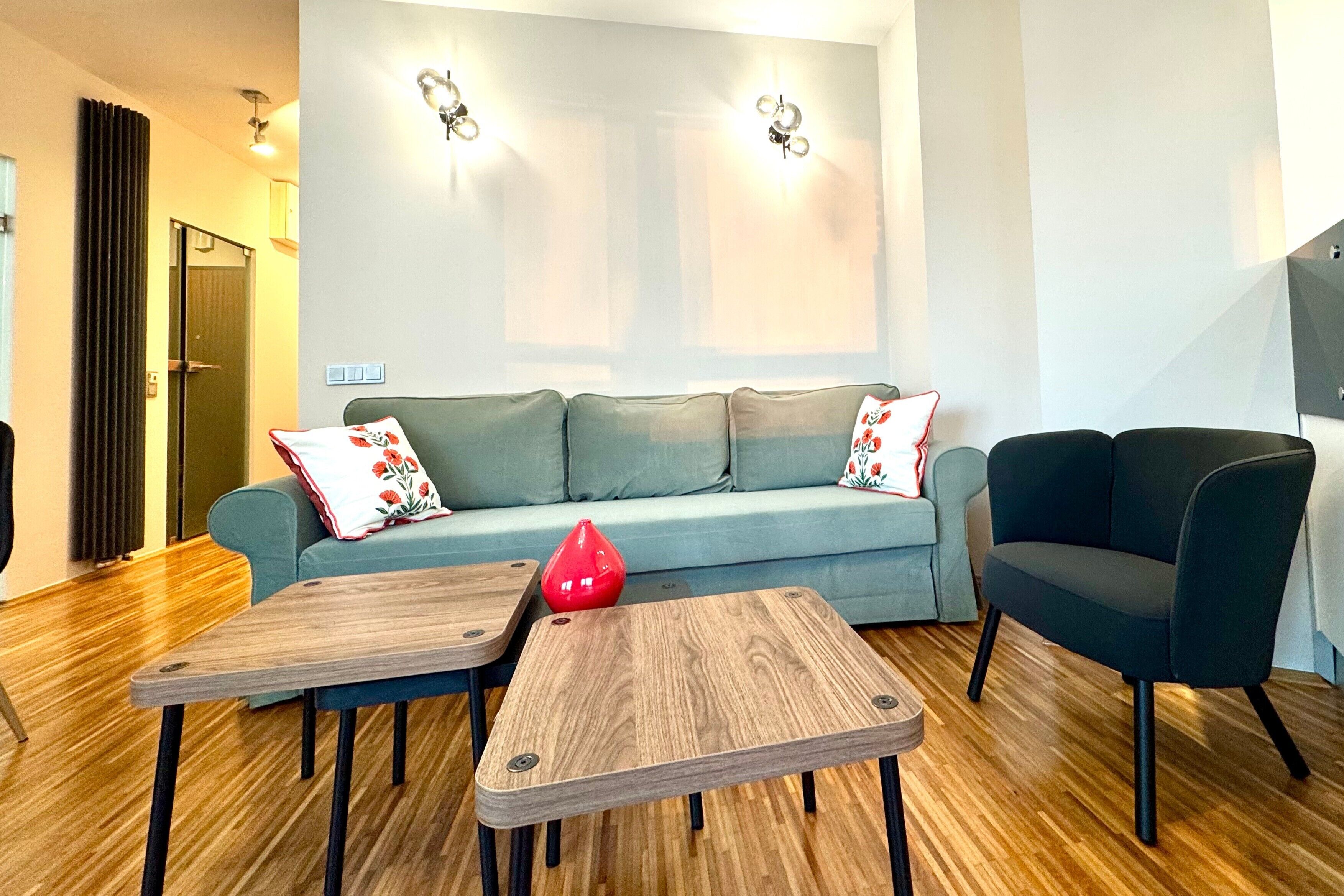 A modern living room with a sofa, two side tables, and a chair.