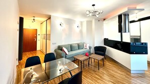 Un salon moderne avec une table à manger en verre, un canapé et un coin cuisine équipé d’une cuisinière.