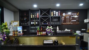 A coffee room with a menu board, bar area with liquor bottles, and a counter with a toaster. - Happy Room Hotel (Chiang Rai)