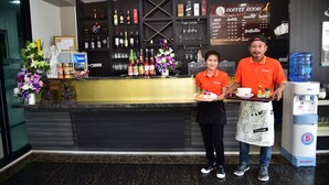 A hotel reception area with a counter, a coffee menu, and a water dispenser. - Happy Room Hotel (Chiang Rai)