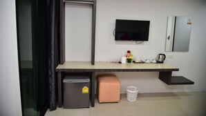 A compact hotel room with a kitchenette, a flat-screen TV mounted on the wall, a small refrigerator, a trash bin, and a cushioned bench. - Happy Room Hotel (Chiang Rai)