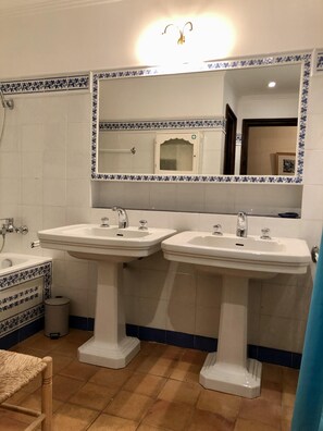 Een badkamer met twee wasbakken, een spiegel en een douche.