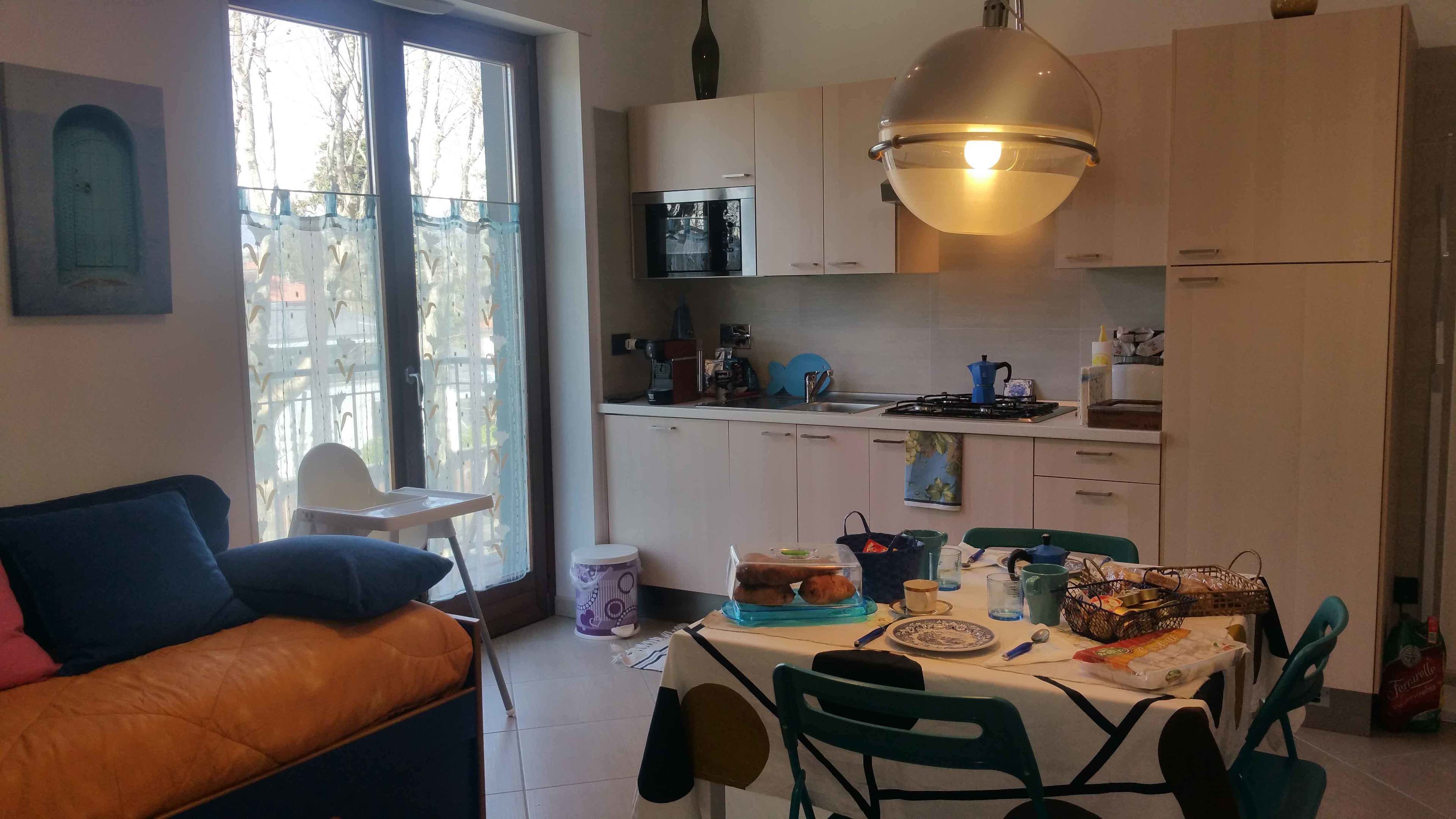Eine kompakte Küche mit Essbereich, einer Couch und Blick durch ein Fenster.