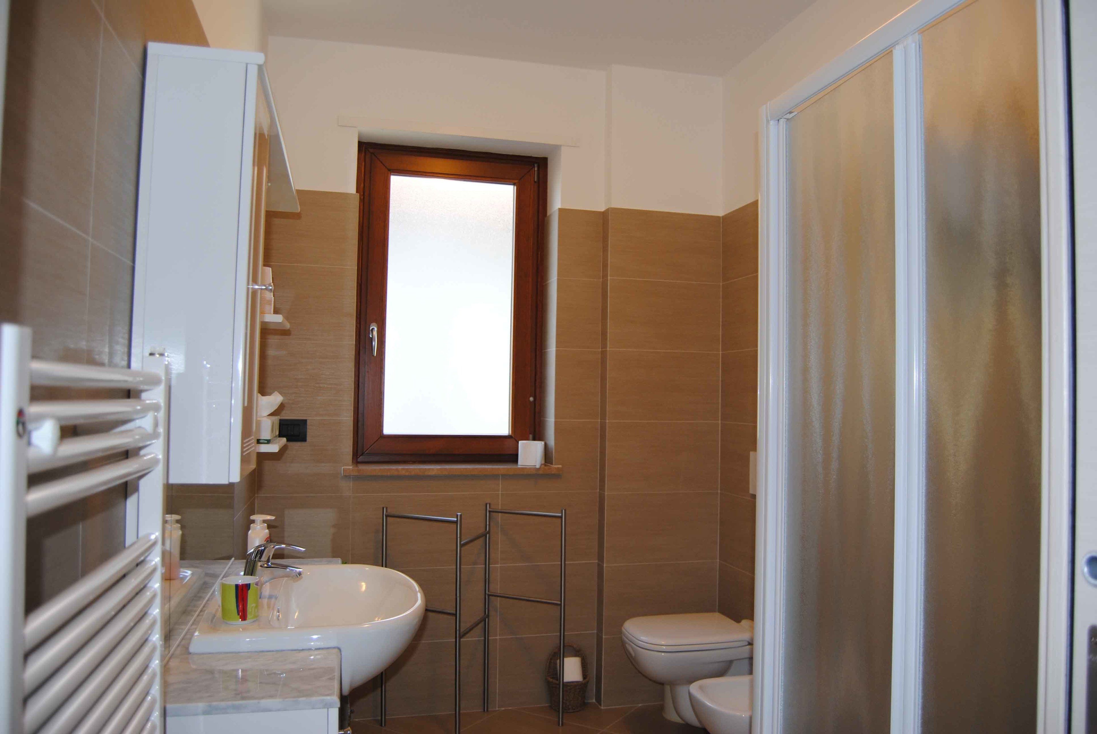 Casa de banho com lavatório branco, sanita e zona de duche.