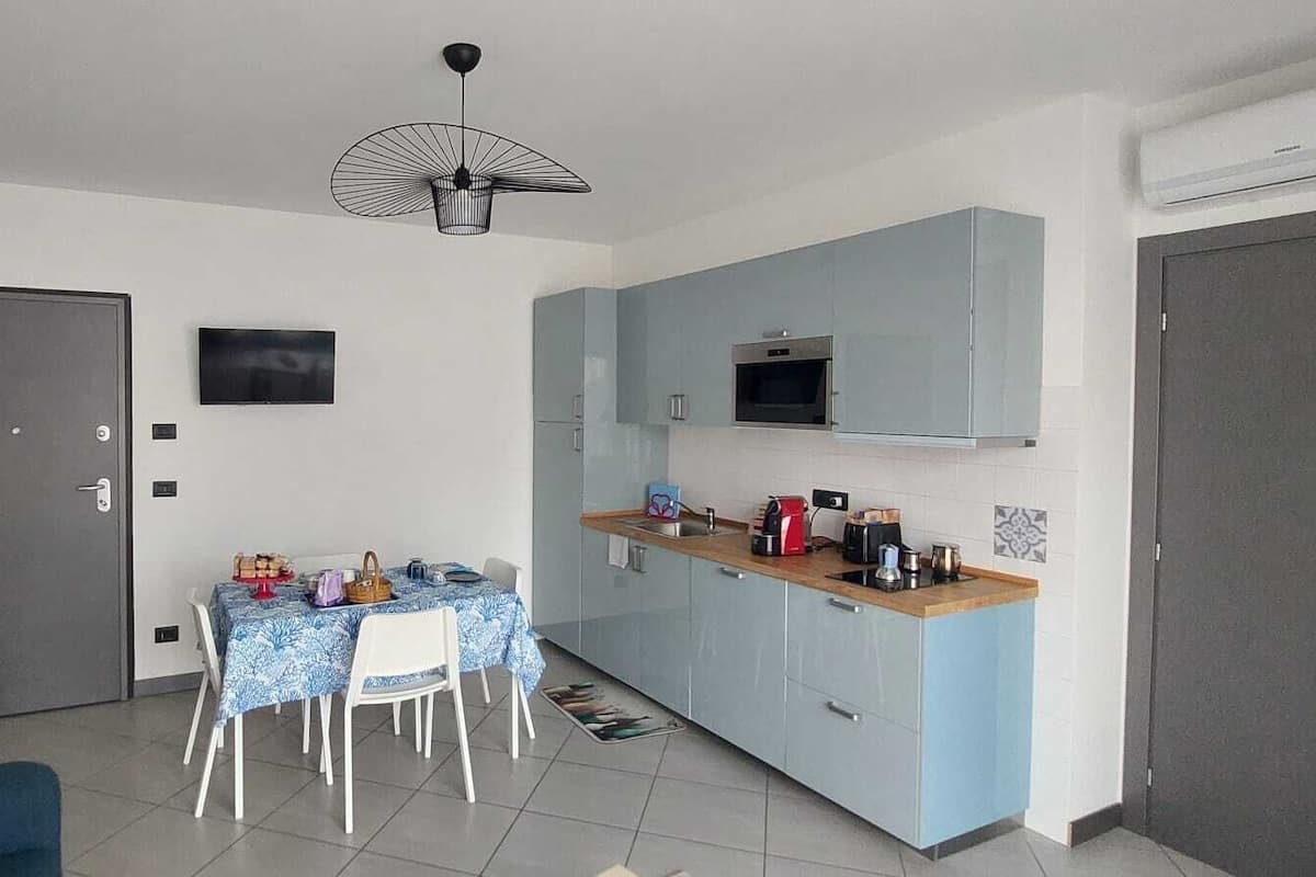 Un espacio habitable compacto con comedor, kitchenette y una puerta gris.