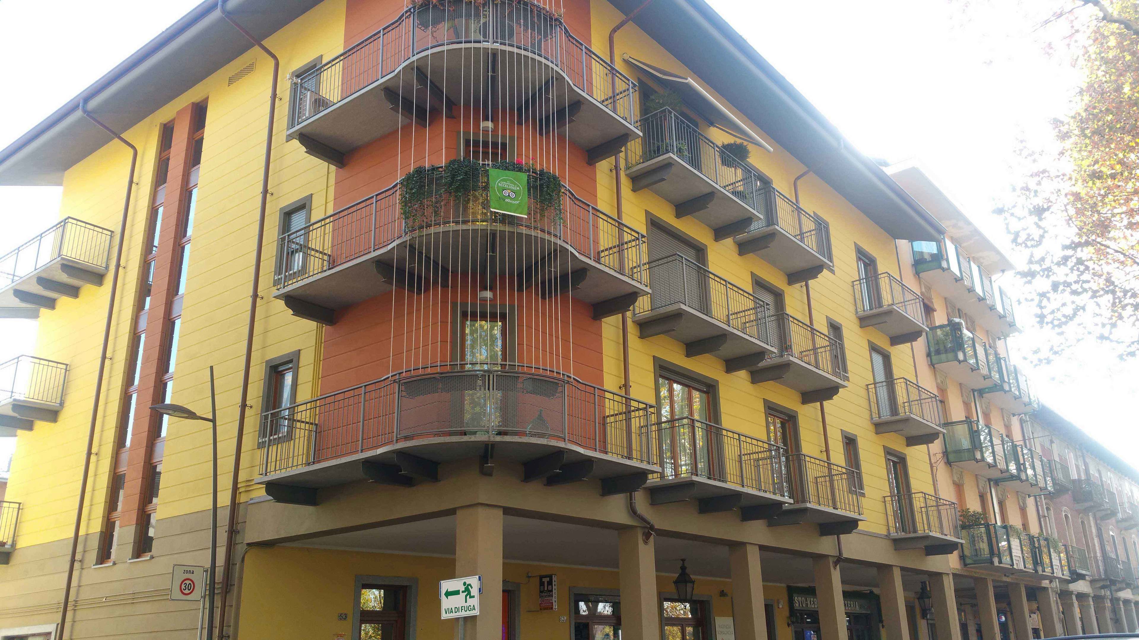Un edificio de varios pisos con balcones, un letrero verde que indica zona de estacionamiento para bicicletas y una señal para peatones.