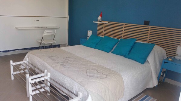 A bedroom with a bed, a nightstand, a chair, and a shelf with a decorative item. - B&B LeTerrazze Boutique Hotel - Torino (Cirie)