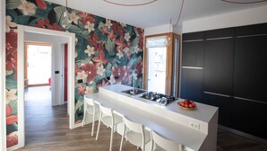 Una cocina moderna con una isla blanca, armarios negros y un mural floral.