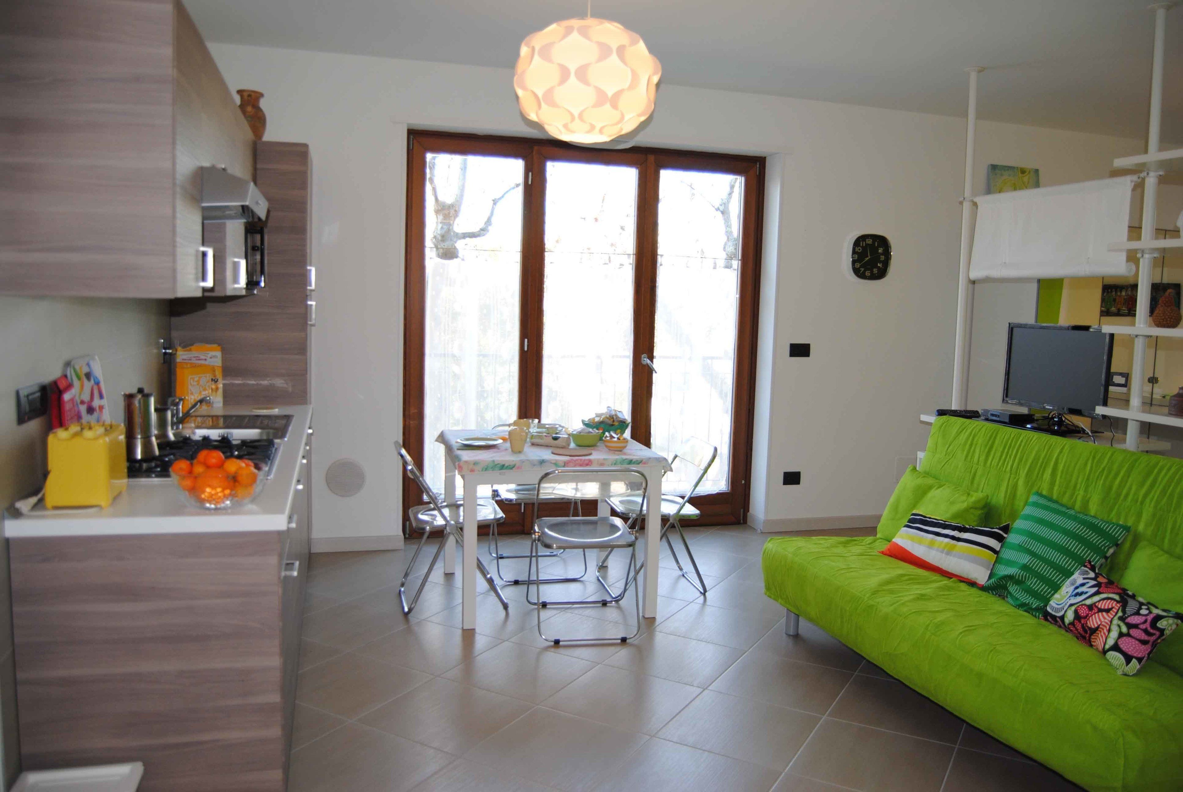 A modern kitchen with a dining table, chairs, and a bright green sofa.