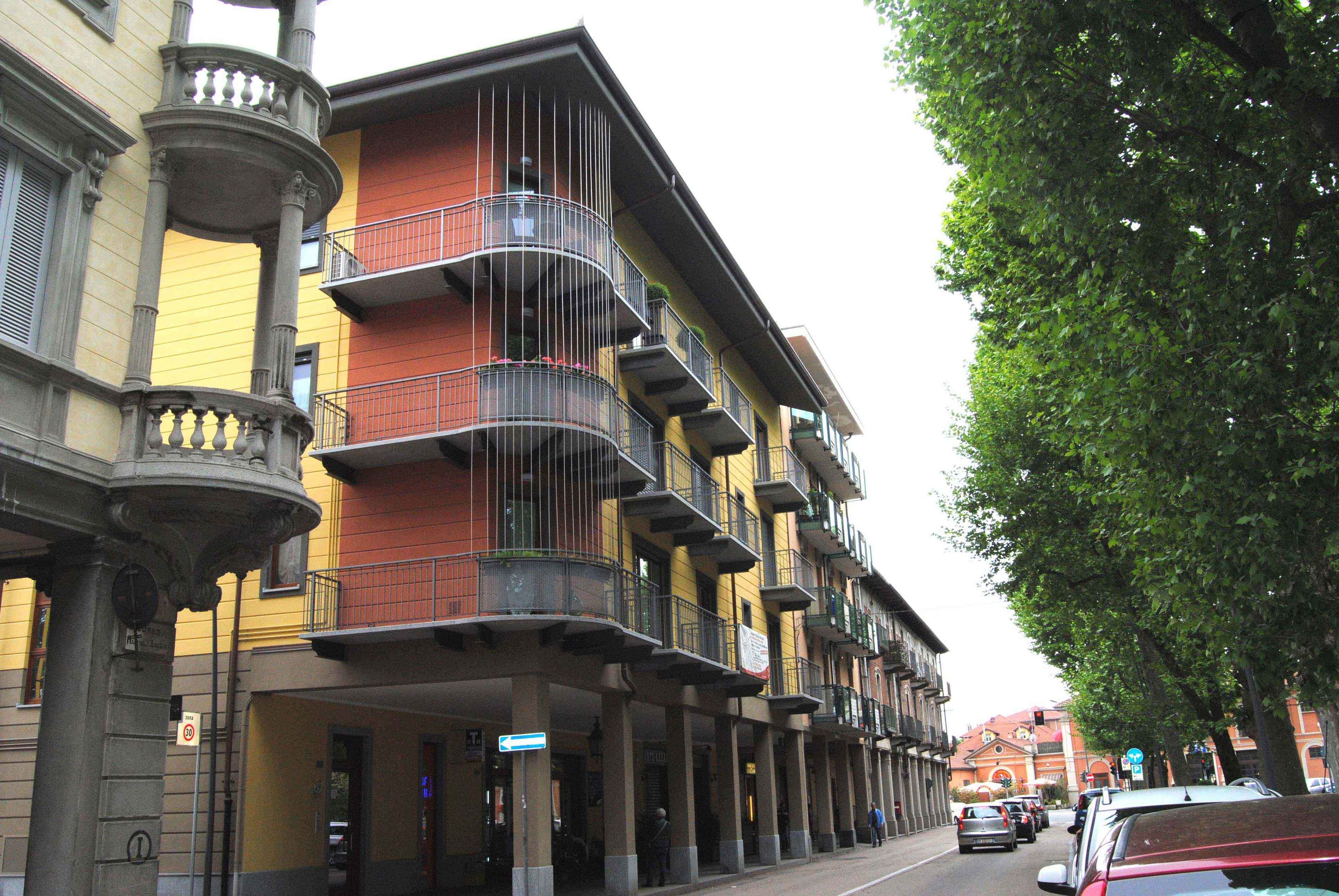 Un edificio a più piani con balconi, un segnale di divieto di parcheggio e un albero sulla destra.