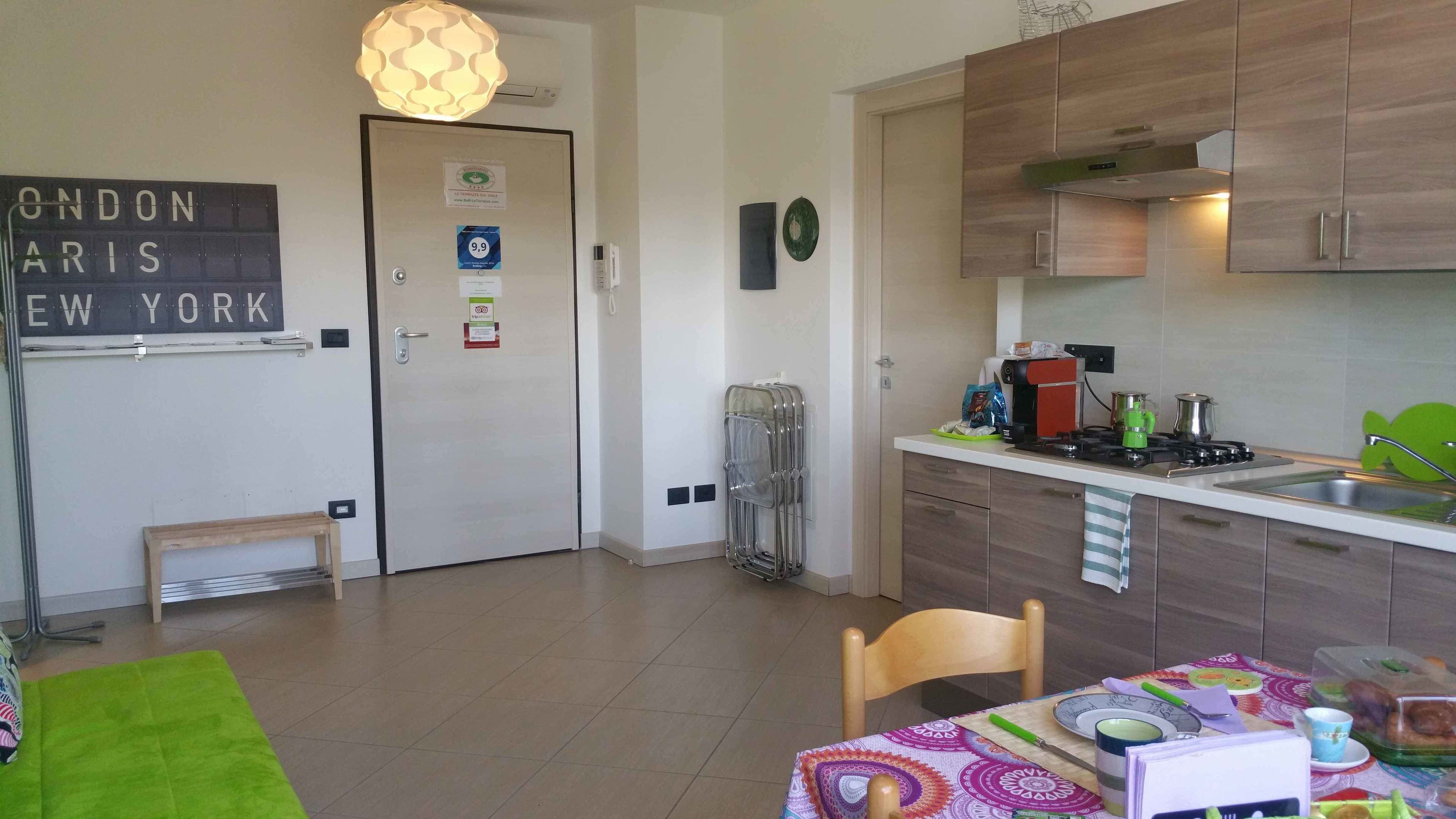 Ett kompakt kök med moderna apparater, en matplats med ett bord för två och en dörr med en skylt som visar vilka städer som ligger i närheten.