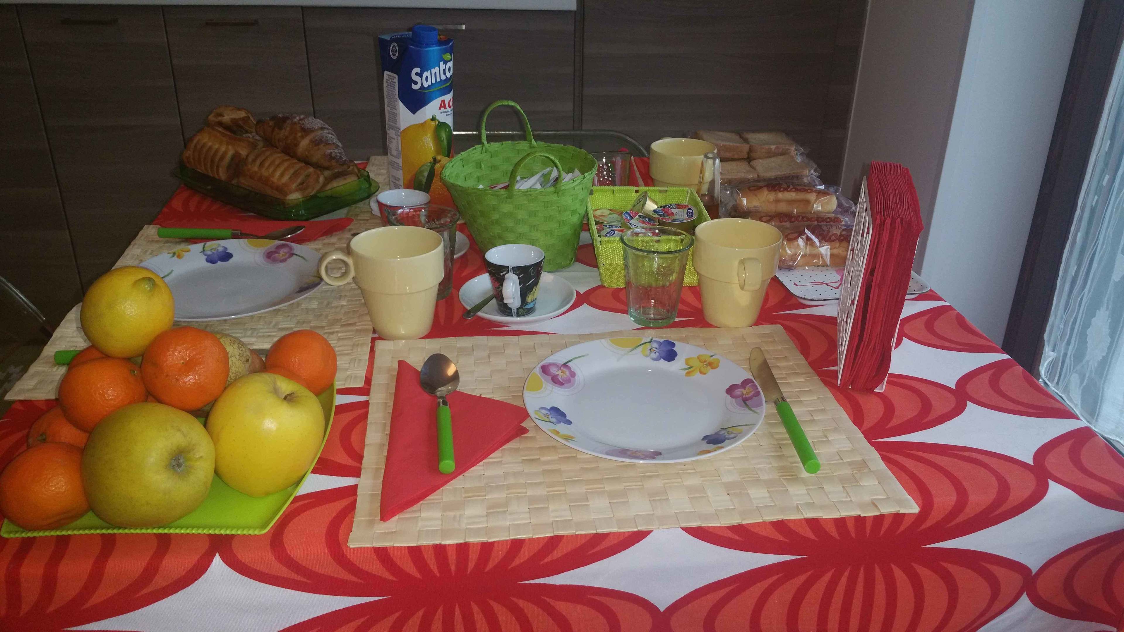A breakfast table with fruits, bread, and beverages.