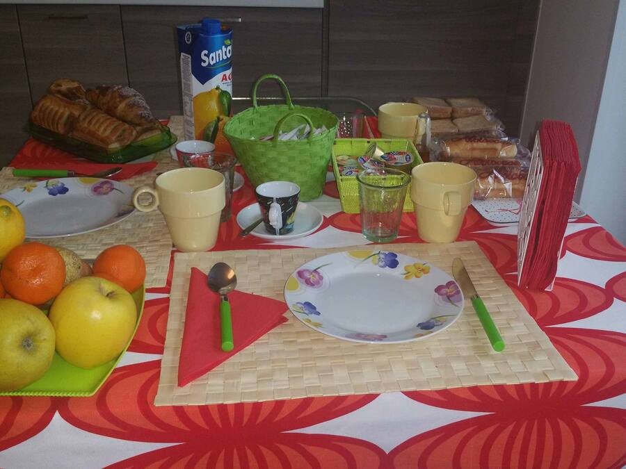 A breakfast table with fruits, bread, and beverages.