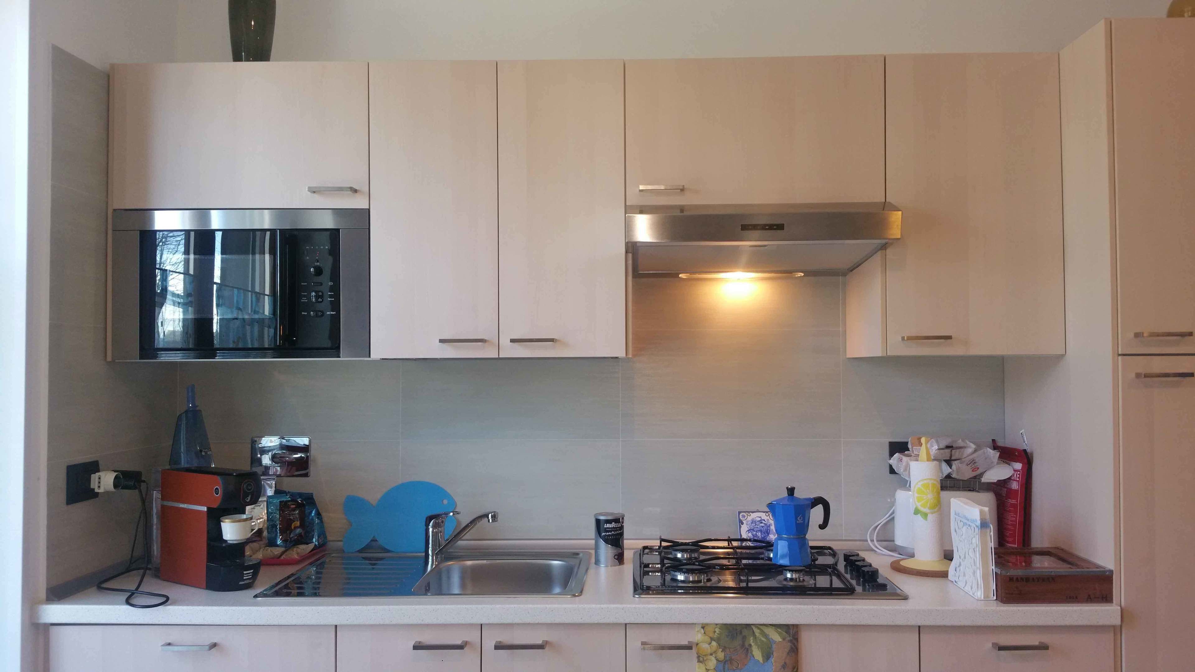 A modern kitchen with light-colored cabinets, a stainless steel microwave, a gas stove, and a sink.