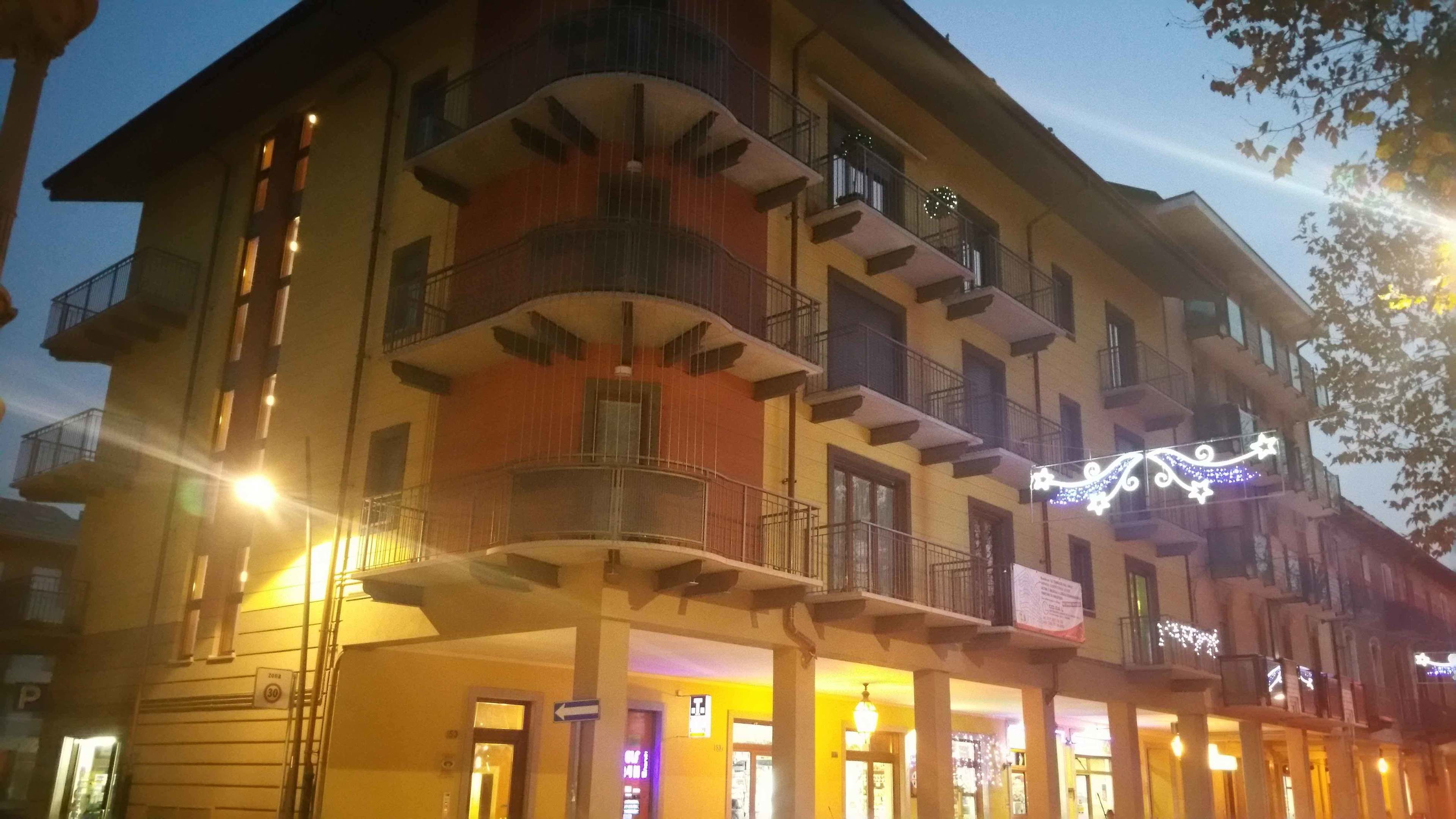 Un hotel de varios pisos con balcones, entrada en la planta baja y un cartel que indica zona de estacionamiento con límite de 30.