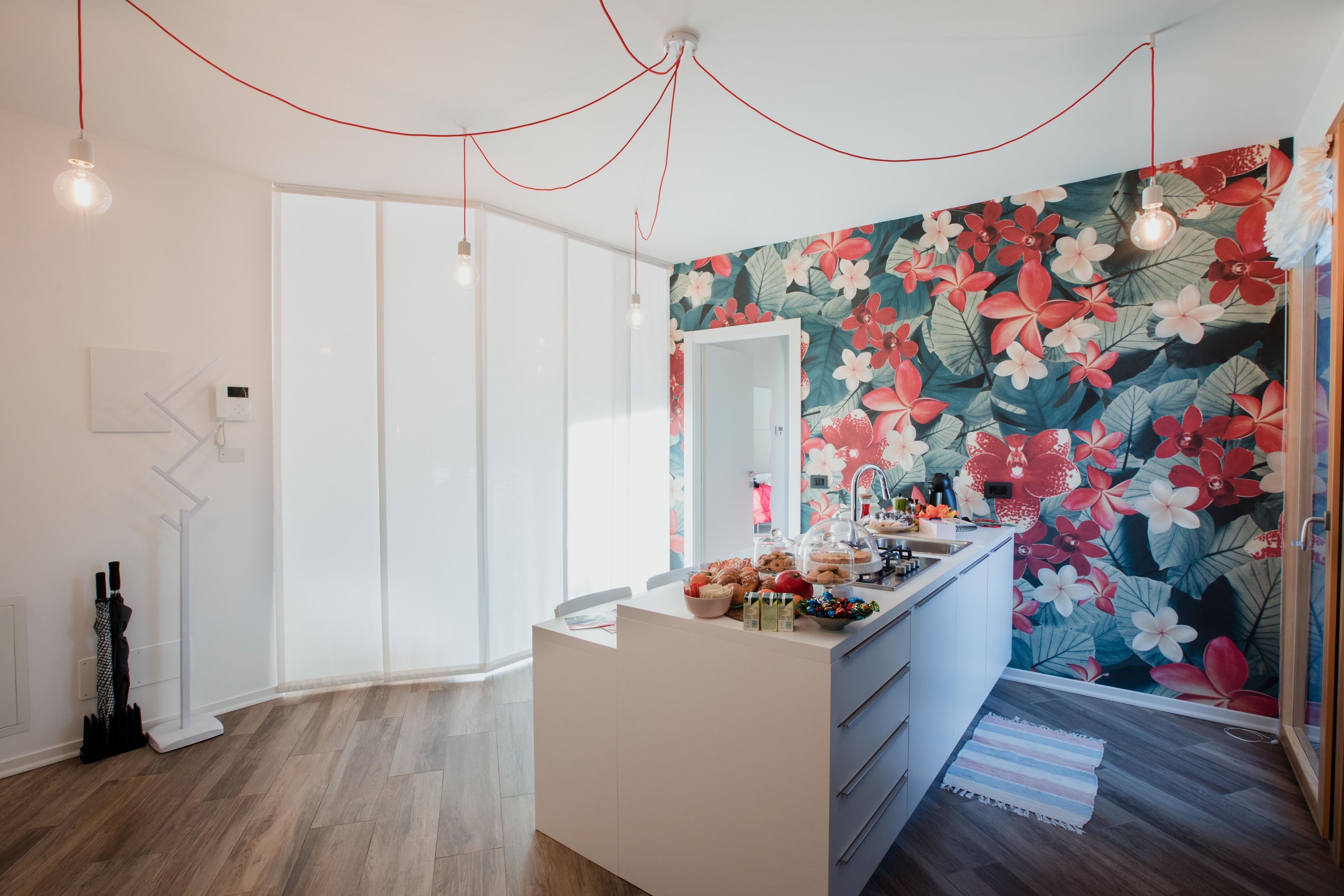 A modern bathroom with a large mirror, a white vanity, and a floral wallpaper.
