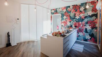 A modern bathroom with a large mirror, a white vanity, and a floral wallpaper.