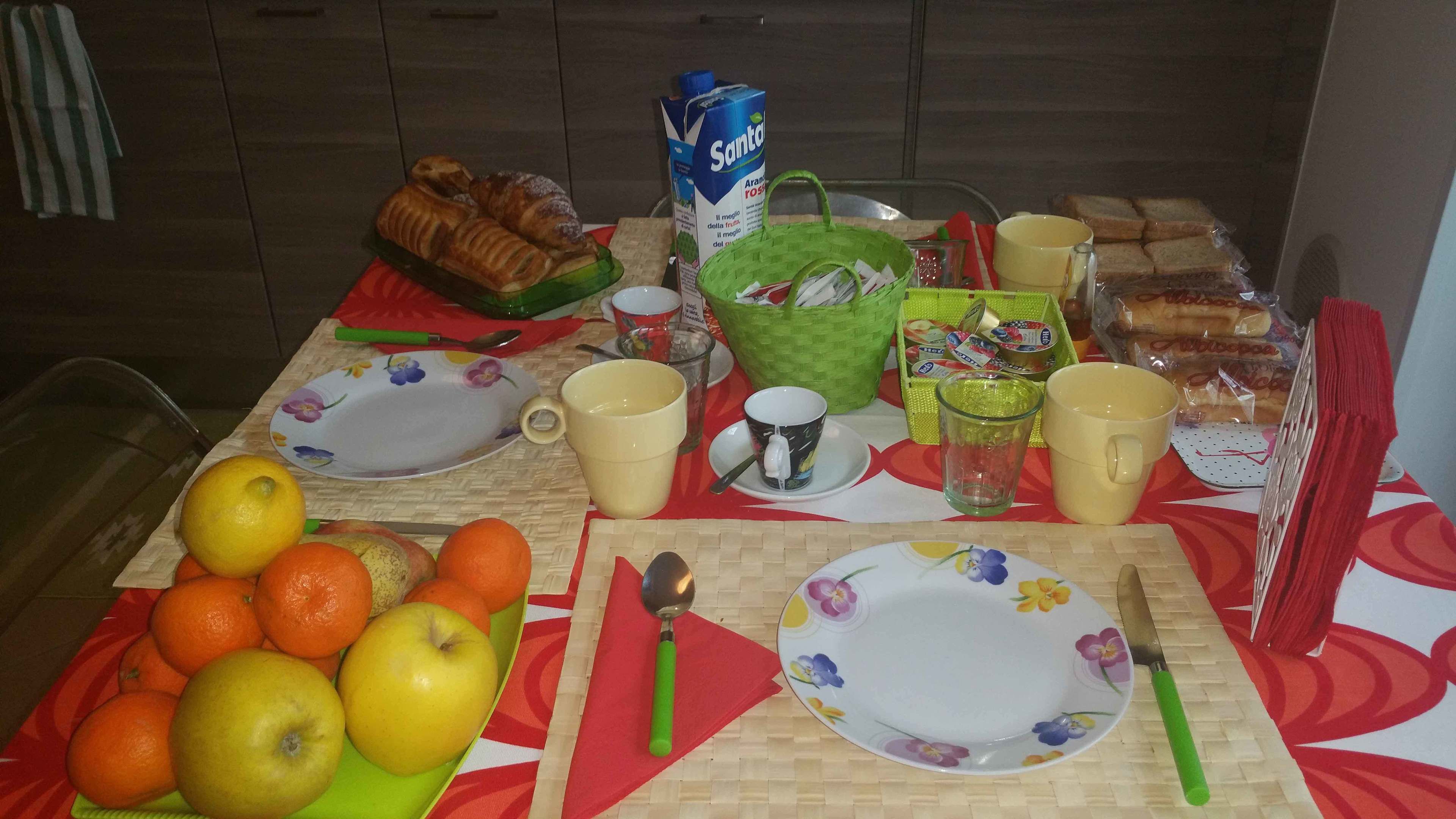 A breakfast table with fruits, bread, and beverages.