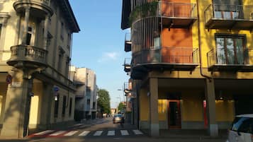 Une rue bordée d’immeubles, dont un immeuble jaune doté d’un balcon et un bâtiment de style classique avec des colonnes.