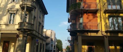 Vista de una calle con edificios que tienen balcones, cielo despejado y un paso de peatones.