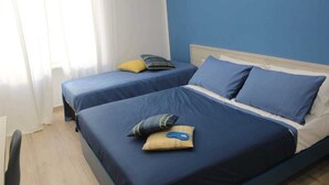 Un dormitorio con dos camas, cada una con ropa de cama y almohadas azules.
