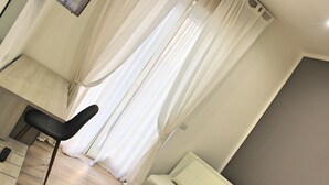 Una habitación con una cama, una silla y un escritorio con un control remoto.