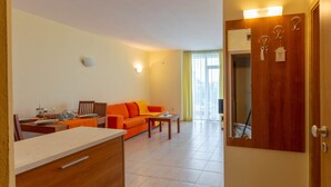 A modern living room with a sofa, a dining table, and a kitchen area. - Large Studio in Polo Resort (Sunny Beach)