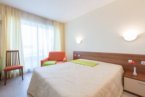 A hotel room with a bed, a chair, a nightstand, and a wall-mounted light. - Quiet Studio in Polo Resort (Sunny Beach)