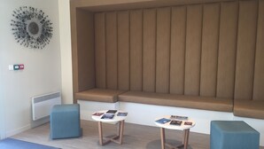 A modern room with a large window seat, a decorative wall piece, and a small table with magazines.