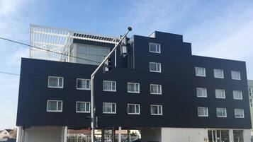 A modern multi-story building with a flat roof, large windows, and a covered entrance area.