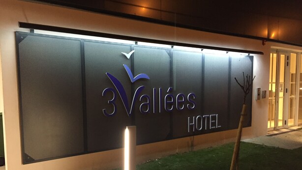 A hotel sign with the name "3 Vallées Hotel" and a logo.