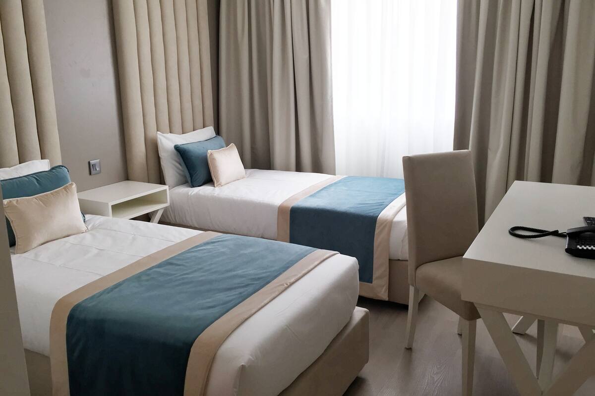Een hotelkamer met twee bedden, een bureau en een stoel.