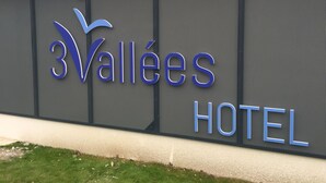 A sign for 3Vallees Hotel with a modern design and a large window display.
