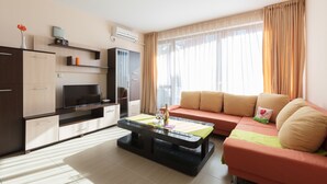 Una sala moderna con un sofá, una mesa de centro, un televisor y un mueble.